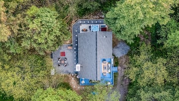 An aerial view of a property with a large building, outdoor seating area, and a hot tub.