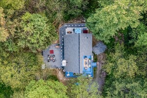 An aerial view of a property with a large building, outdoor seating area, and a hot tub.