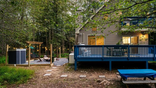 A house with a deck, a swing set, and a small outdoor seating area. - Poconos Pines Escape Sauna Hot Tub Playground (Pocono Lake)