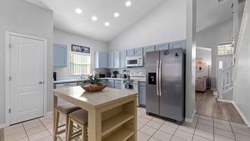 A modern kitchen with a central island, stainless steel appliances, and light blue cabinetry.