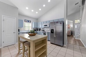 A modern kitchen with a central island, stainless steel appliances, and light blue cabinetry. - 12 min to Disney Movie Theater Pool In-ground spa (Davenport)