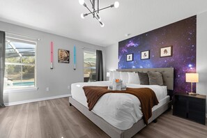 A modern bedroom with a large bed, a galaxy-themed wall, and a view of a swimming pool. - 12 min to Disney Movie Theater Pool In-ground spa (Davenport)