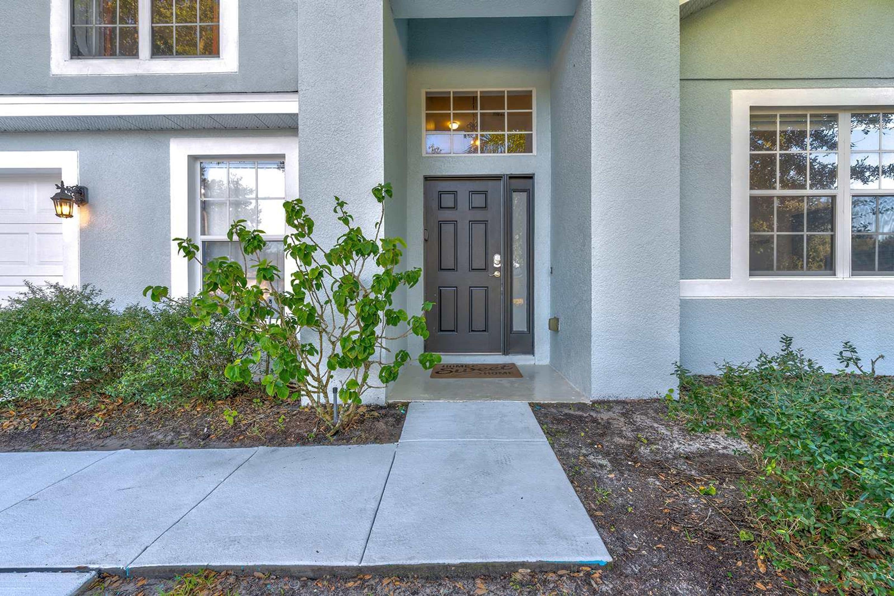 A residential house with a front door, a small porch, and a window above the door.