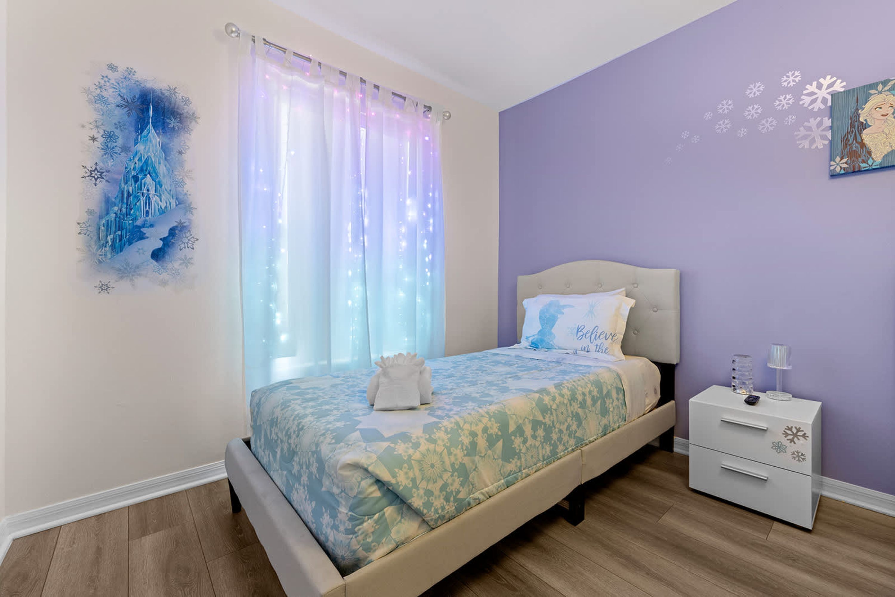 A bedroom with a bed, a nightstand, and a wall decoration.