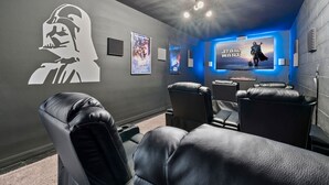 Sala de cinema com parede temática de Star Wars, ventilador de teto e assentos de couro.