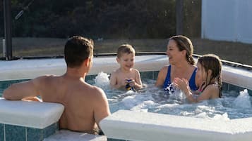 A family of four in a hot tub with a tiled exterior.