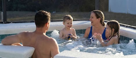 A family of four in a hot tub with a tiled exterior.