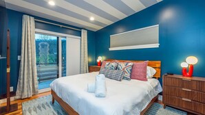 A bedroom with a bed, a nightstand, a lamp, a window with curtains, and a view of the outdoors. - Mountain Retreat Sauna Outdoor Dining Nature (Asheville)