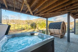 Ein Whirlpool und eine Sauna unter einem Holzdach mit Blick auf eine hügelige Landschaft.