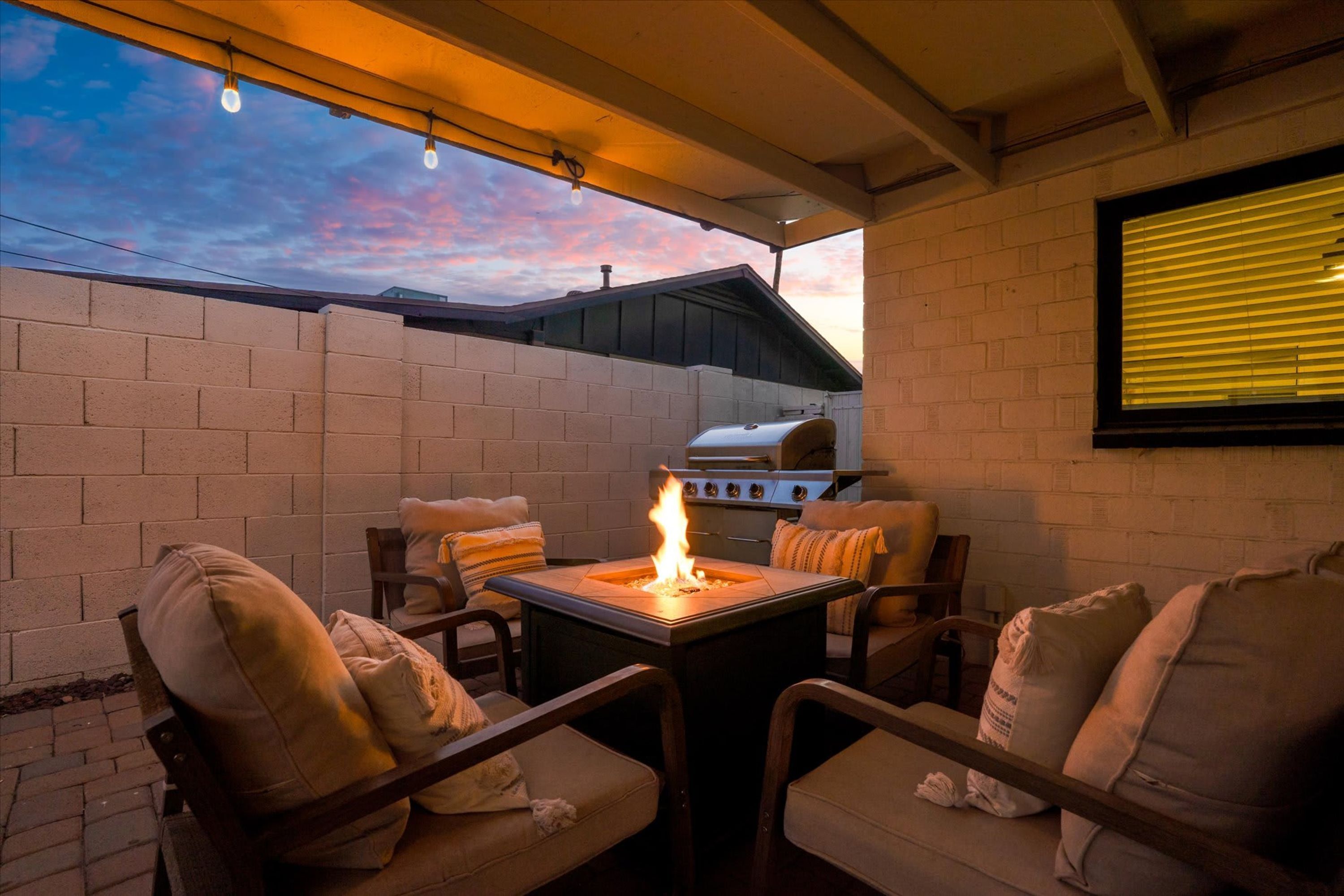 Eine Terrassenanlage im Freien mit Feuerstelle, Sitzgelegenheiten und Grill.