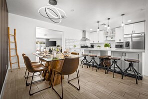 Eine moderne Küche mit einer Kochinsel, Barhocker und einem Essbereich mit Stühlen.
