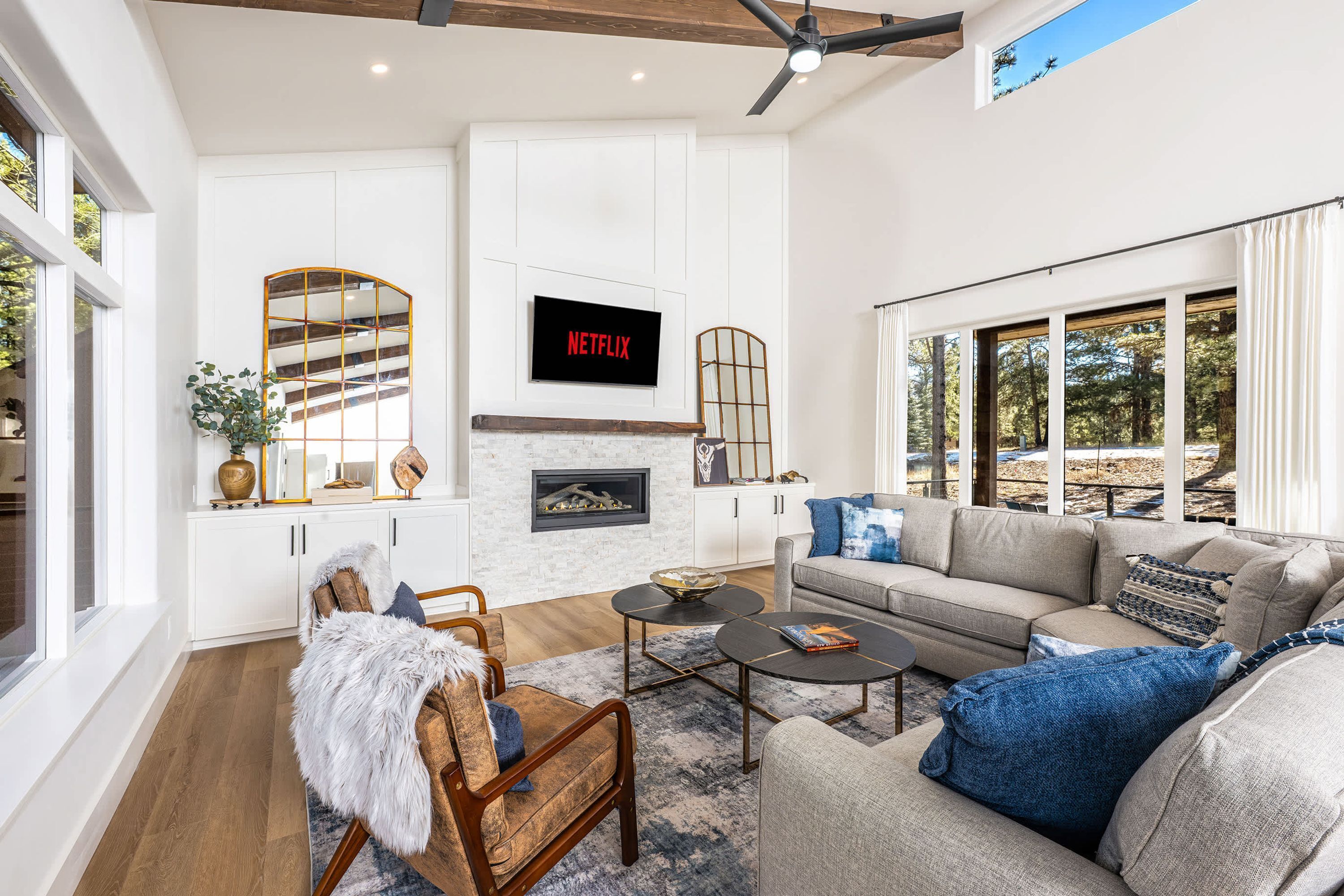 A modern living room with a fireplace, a sofa, a coffee table, and a television mounted on the wall.