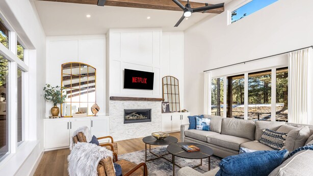 A modern living room with a fireplace, a sofa, a coffee table, and a television mounted on the wall. - The Pines of Valle Grande Hot Tub Fireplace (Angel Fire)