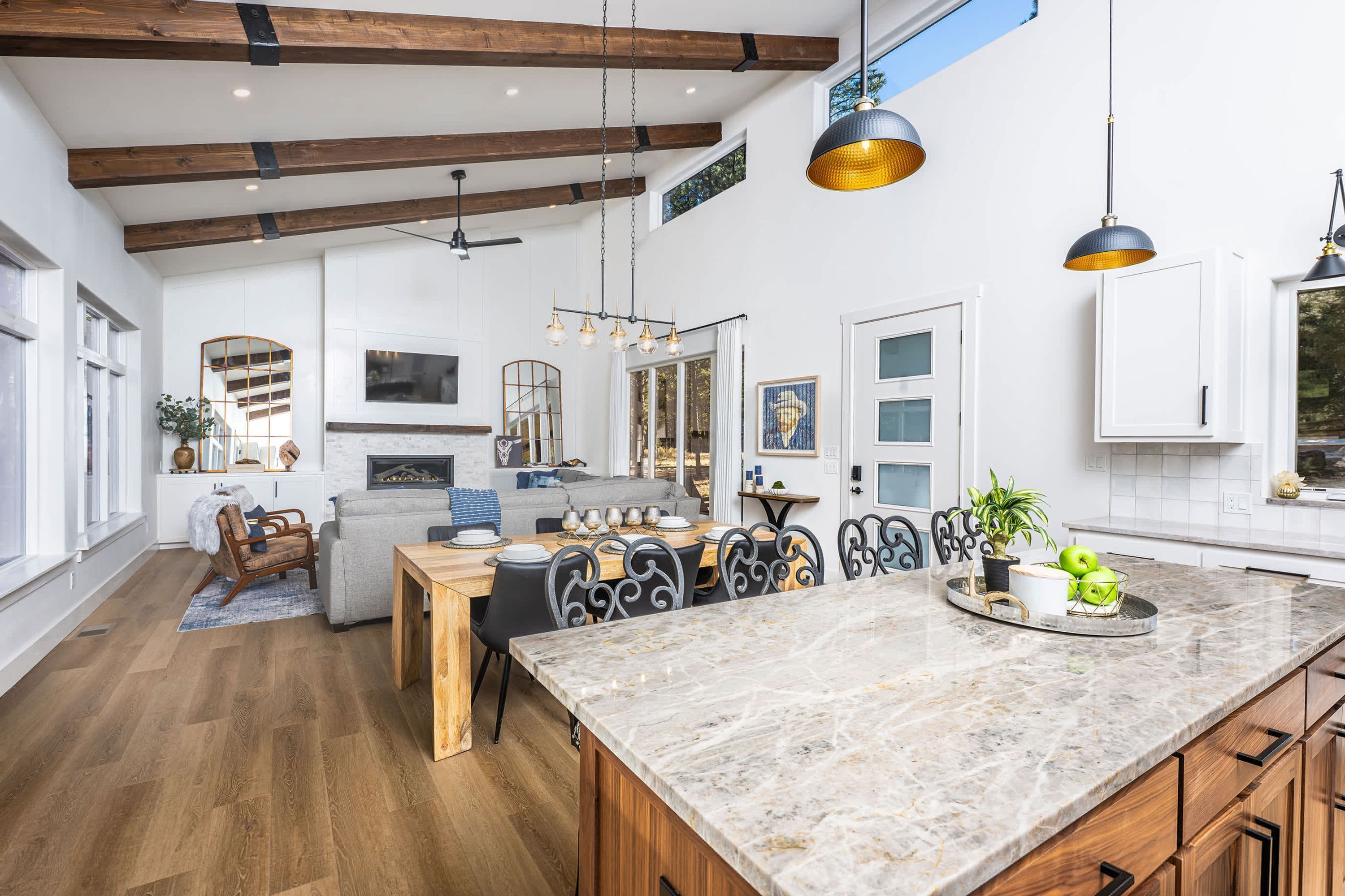 A spacious kitchen with a large island, wooden beams, and pendant lighting.