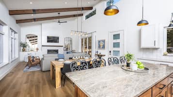 Una cocina amplia con una isla grande, vigas de madera e iluminación colgante.