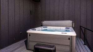 A hot tub with a wooden deck and a metal railing. - The Pines of Valle Grande Hot Tub Fireplace (Angel Fire)