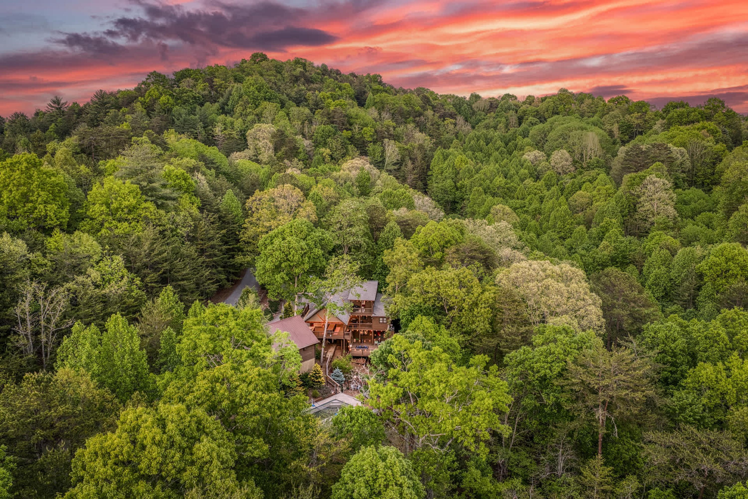 Ein zweistöckiges Lodge, umgeben von dichtem Wald, mit einer sichtbaren Straße dorthin.