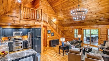 A spacious cabin with a kitchen, dining area, and a large living room with a fireplace.