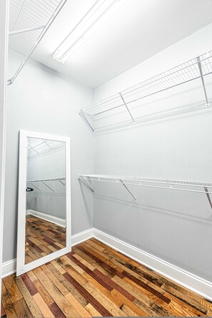 A room with a wooden floor, white walls, and a mirrored closet door. - Cozy Family Getaway w Games Hot Tub Fire Pit (Bryson City)