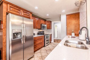 A modern kitchen with stainless steel appliances, wooden cabinetry, and a large island with a sink. - Cozy Family Getaway w Games Hot Tub Fire Pit (Bryson City)