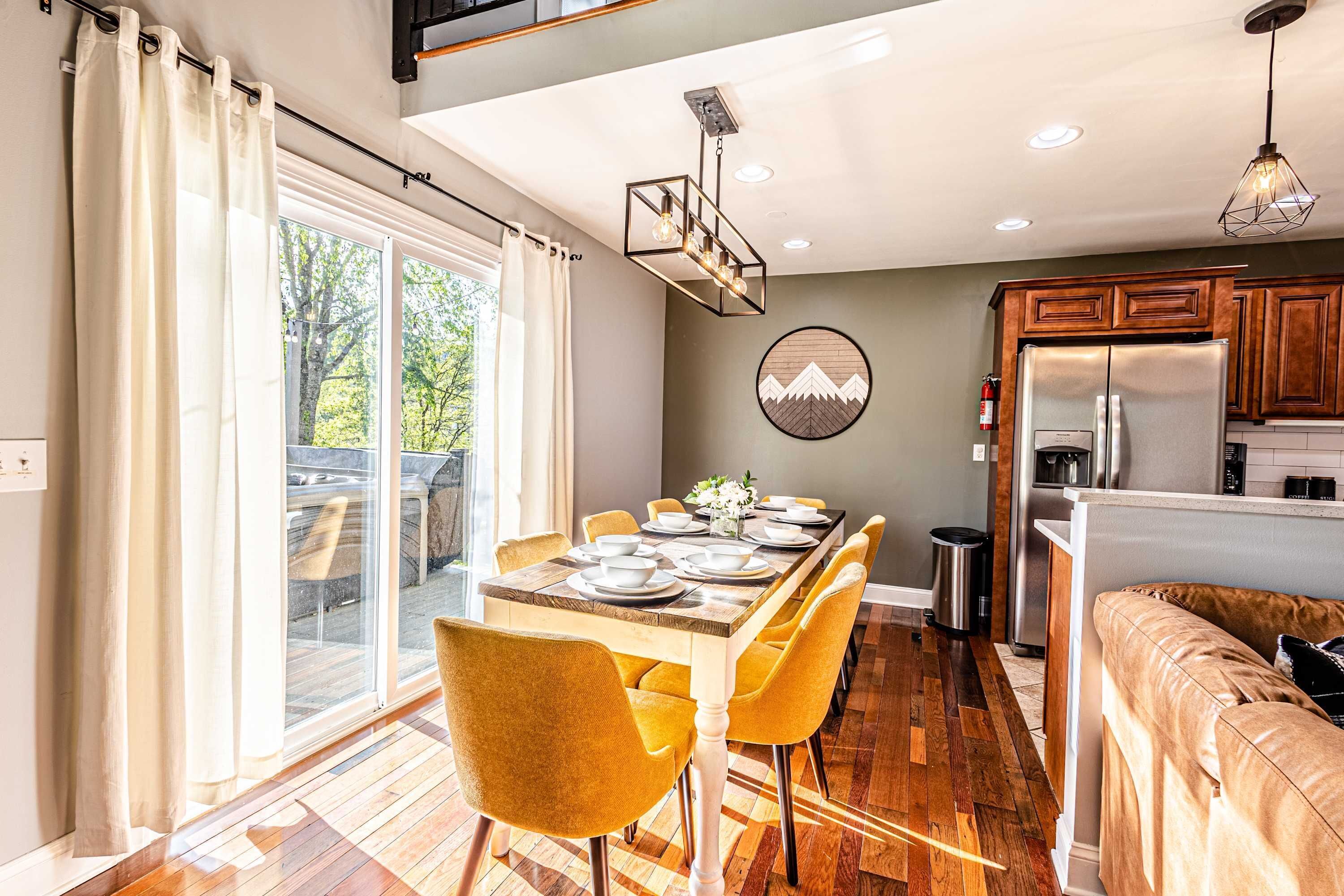 A modern kitchen with a built-in refrigerator, wooden cabinets, and a dining area with a table set for four.