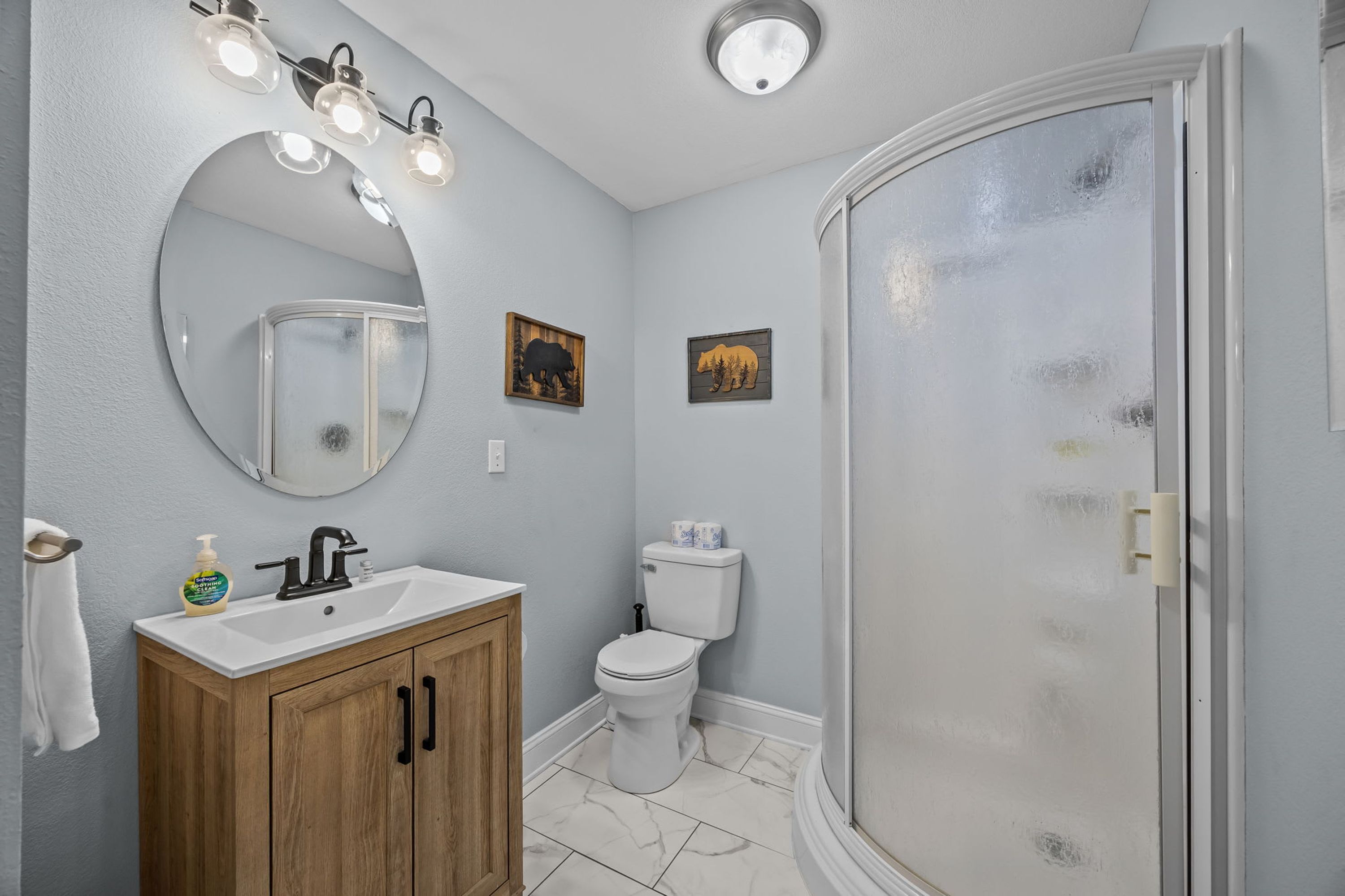 A bathroom with a white sink, a mirror, a toilet, and a glass-enclosed shower.