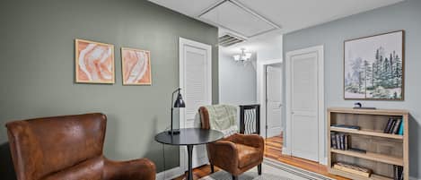 A room with a brown leather chair, a round table, and a bookshelf.