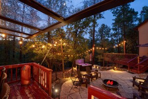 An outdoor patio area with a hot tub, seating, and string lights. - Wildlife Views Hot Tub Fire Pit Games (Prescott)