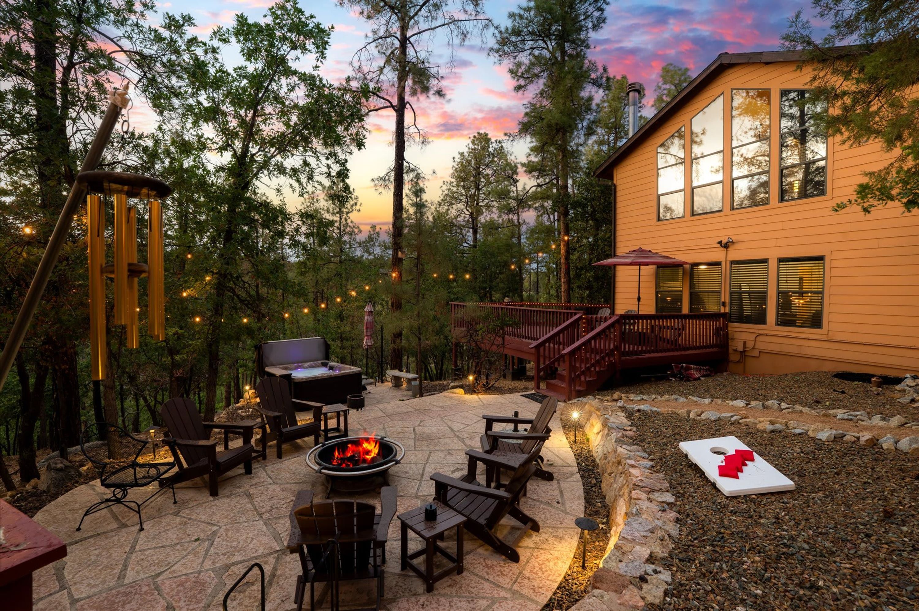 A patio area with outdoor seating, a hot tub, and a deck leading to a house.