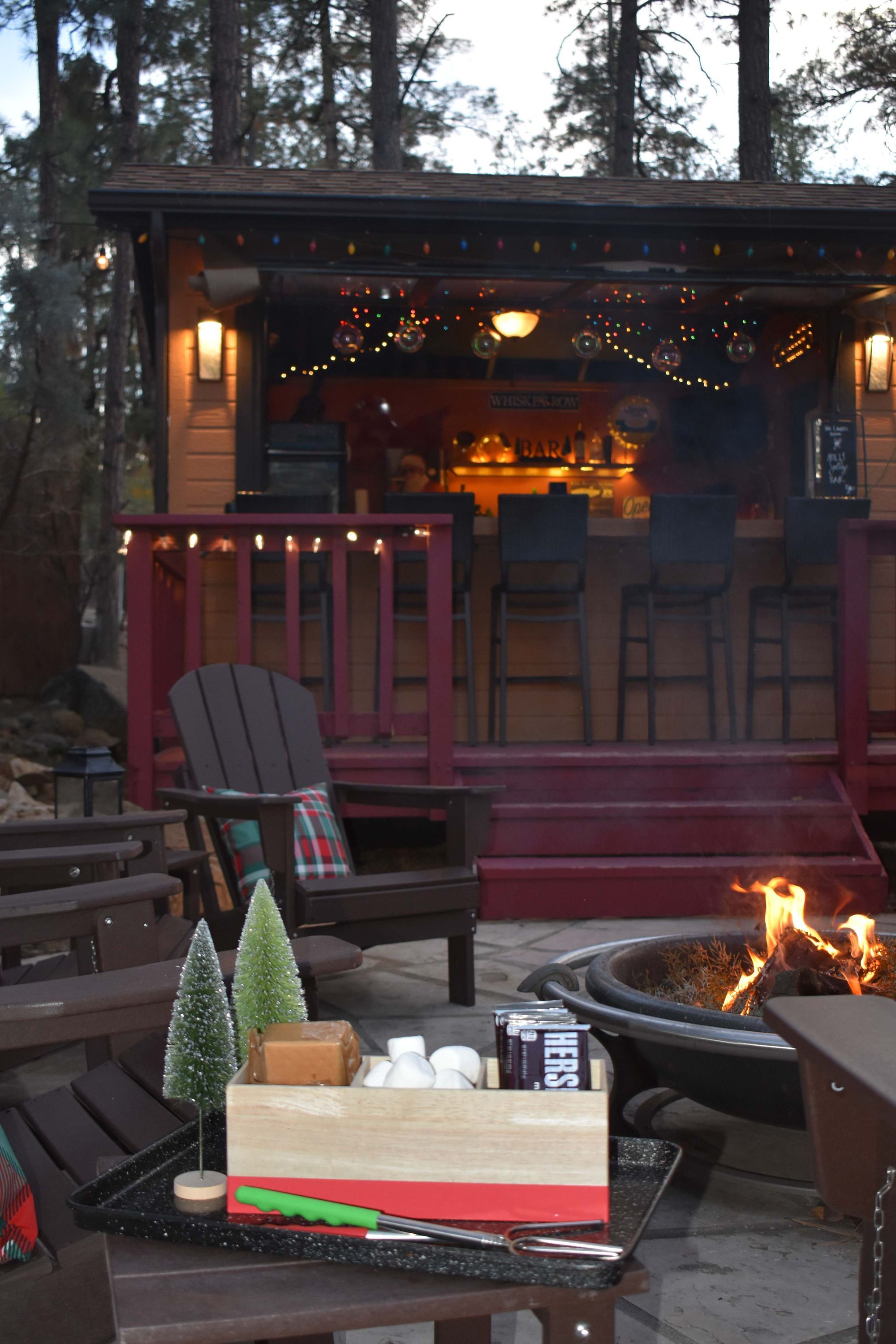 A wooden deck with outdoor seating, a fire pit, and a small Christmas tree.