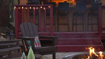 A wooden deck with outdoor seating, a fire pit, and a small Christmas tree.
