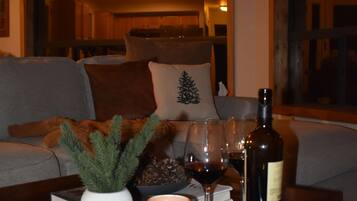 A cozy living room with a wooden coffee table holding a candle, a bottle, and glasses.