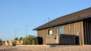 A wooden building with a covered grill area, outdoor seating, and string lights.