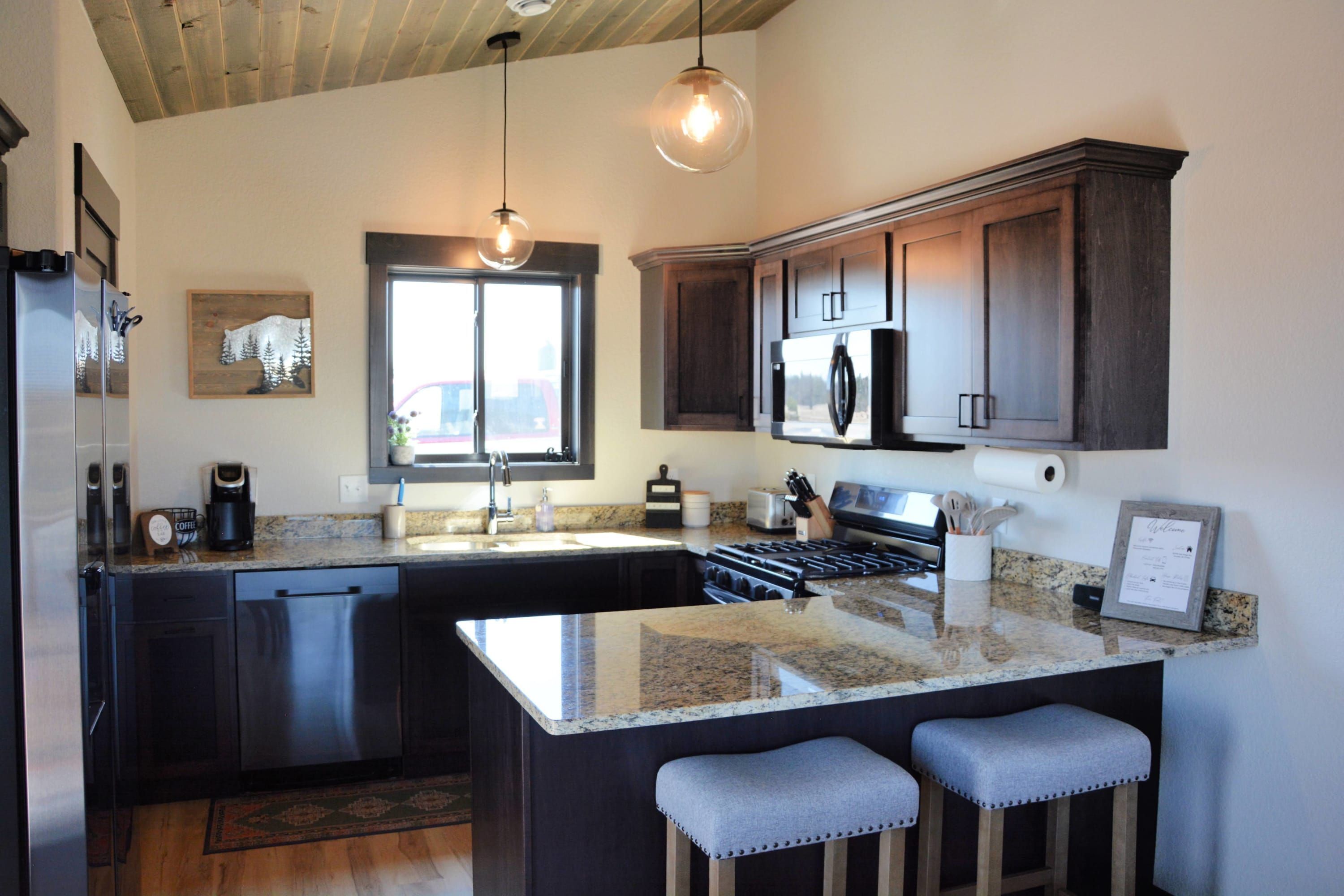 A kitchen with dark wood cabinets, a stainless steel refrigerator, a built-in oven, and a granite countertop.
