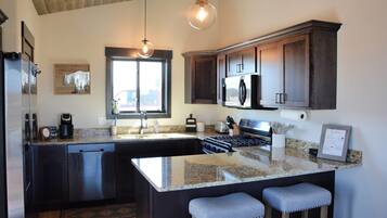 A kitchen with dark wood cabinets, a stainless steel refrigerator, a built-in oven, and a granite countertop.