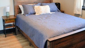 Een slaapkamer met een houten bed, een nachtkastje en een lamp.
