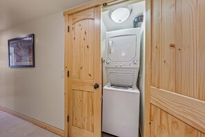 A laundry room with a built-in washer and dryer, wooden doors, and a framed picture on the wall. - Mountain Retreat Canoe Fireplace Views (Soda Springs)