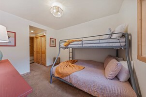 Habitación con literas, un escritorio, un armario de madera y un cuadro en la pared.