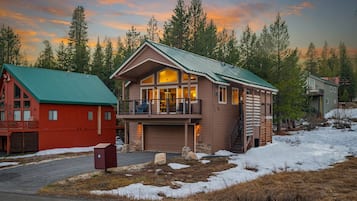 A two-story house with a green roof, a garage, and a balcony.