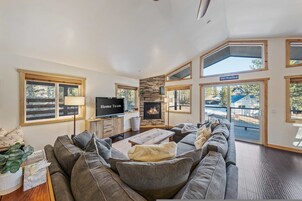 Un salón amplio con chimenea de piedra, un televisor de pantalla plana grande y una zona de estar cómoda.