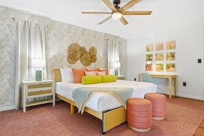 A bedroom with a bed, bedside tables, a desk, a ceiling fan, and wall art. - Sleeps 12 Game Room Theatre Tiki Bar Pool (Bradenton)