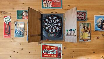 Eine Dartscheibe, umgeben von Werbeanzeigen für Coca-Cola im Vintage-Stil.