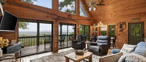 A cabin interior with a large deck, seating area, and a television.