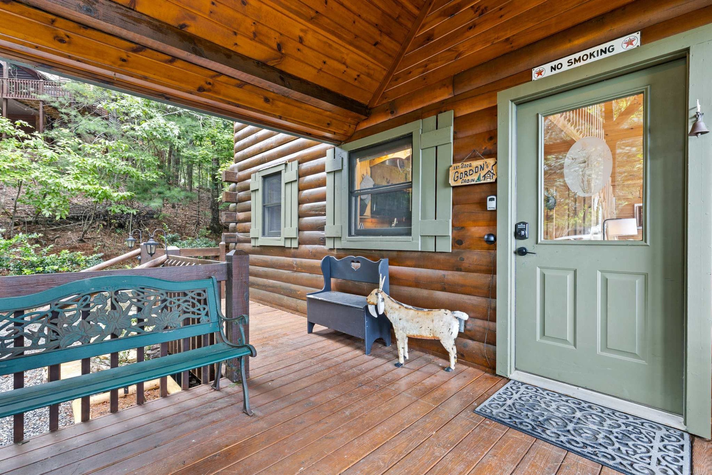 A wooden cabin with a porch, a bench, a goat sculpture, and a door with a 'No Smoking' sign.