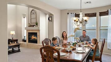 A dining room with a fireplace, chandelier, and a view of the outdoors.