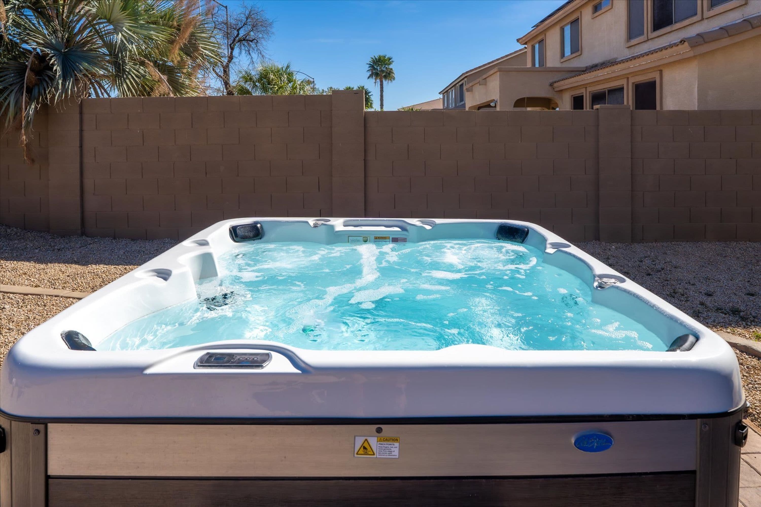 A hot tub with a control panel, surrounded by a brick wall and palm trees.