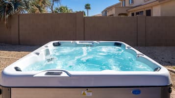 A hot tub with a control panel, surrounded by a brick wall and palm trees.
