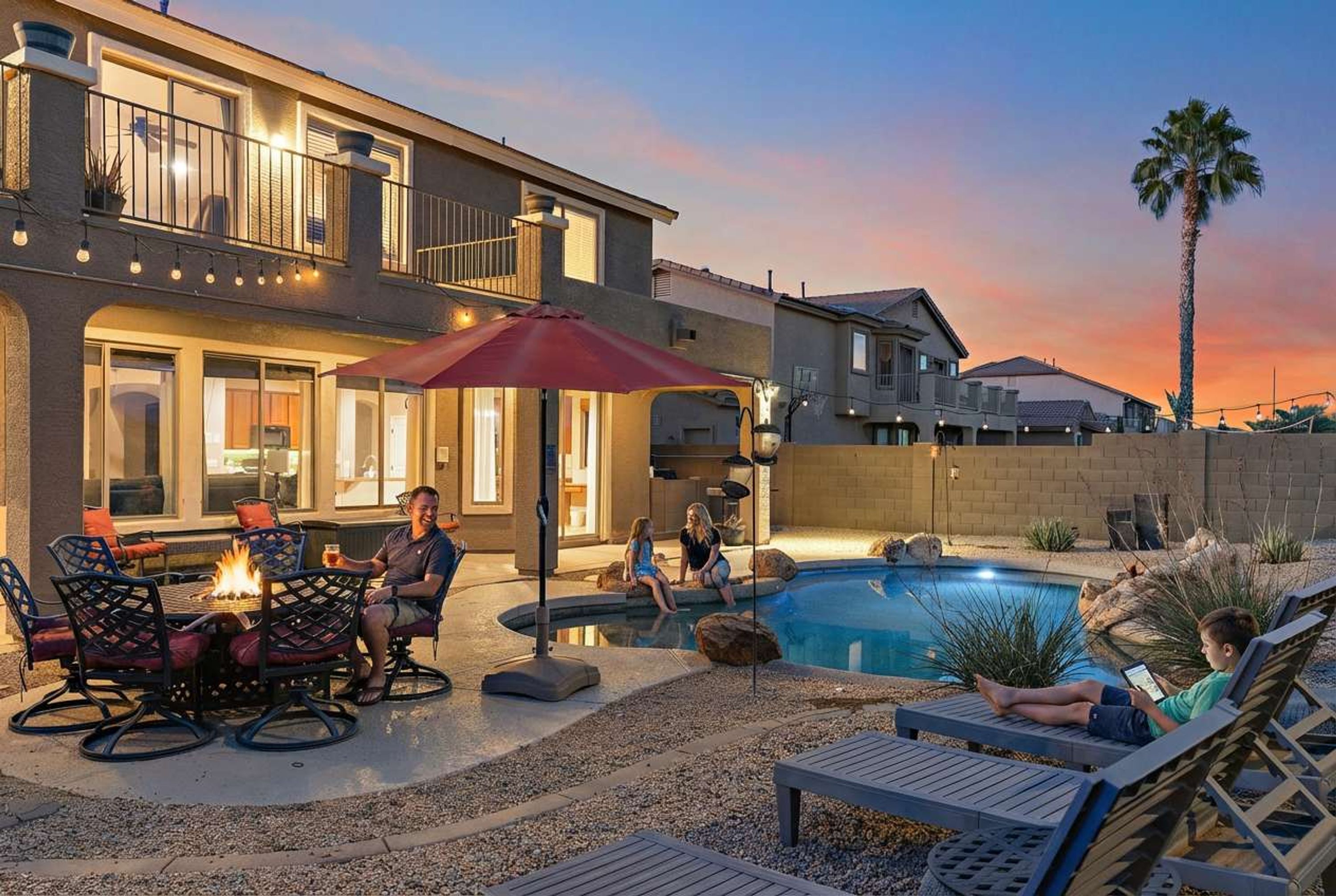 A residential property with a swimming pool, outdoor seating, and a well-lit patio area.