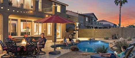 A residential property with a swimming pool, outdoor seating, and a well-lit patio area.