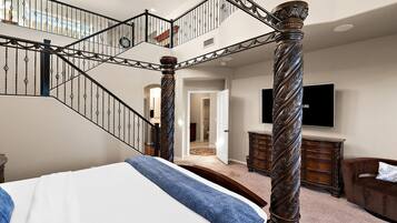 A bedroom with a large bed, a wooden dresser, and a staircase with ornate railings.